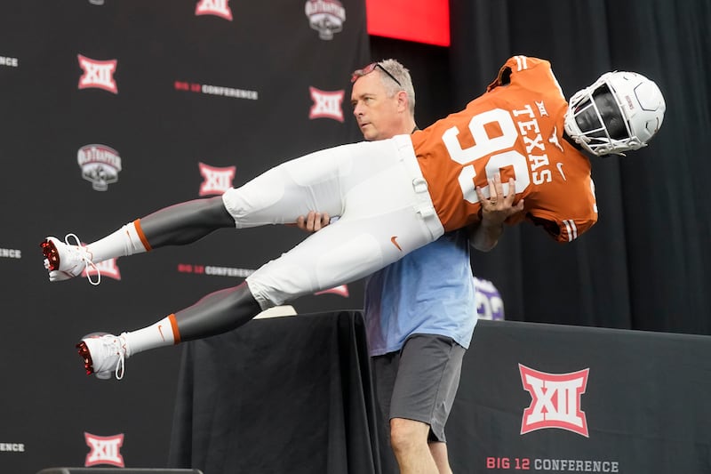 Brad Clements carries off a mannequin wearing a Texas uniform as he dismantles the stage after the Big 12 media days.