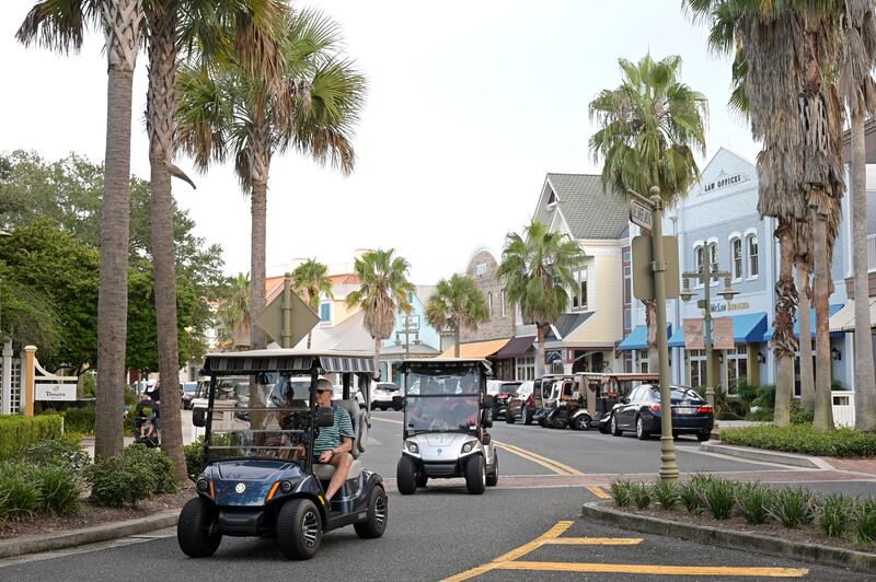 Residents drive golf carts through the Lake Sumter Landing Market Square.