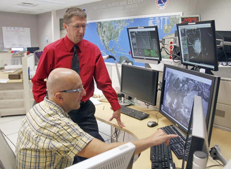 Dr. Lixion Avila, senior hurricane specialist, foreground, updates Dr. Rick Knabb, director of the National Hurricane Center, on other developing tropical storms Wednesday, Aug. 22, 2012, at the National Hurricane Center in Miami. The U.S. National Hurric