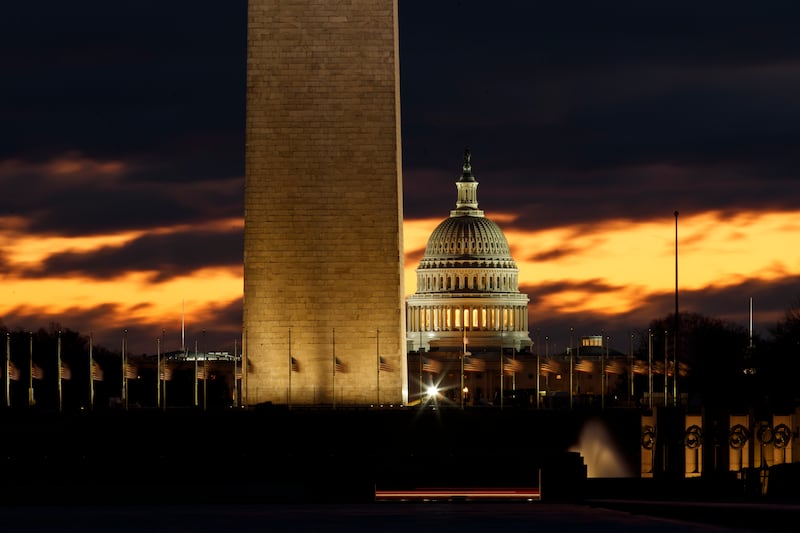 The U.S. Capitol dome is seen past the base of the Washington Monument just before sunrise in Washington, Saturday, Dec. 22, 2018.