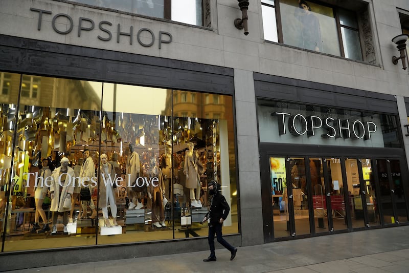A person wearing a face mask to try to curb the spread of coronavirus walks past the temporarily closed Topshop flagship store on Oxford Street, during England’s second coronavirus lockdown, in London, Monday, Nov. 30, 2020.