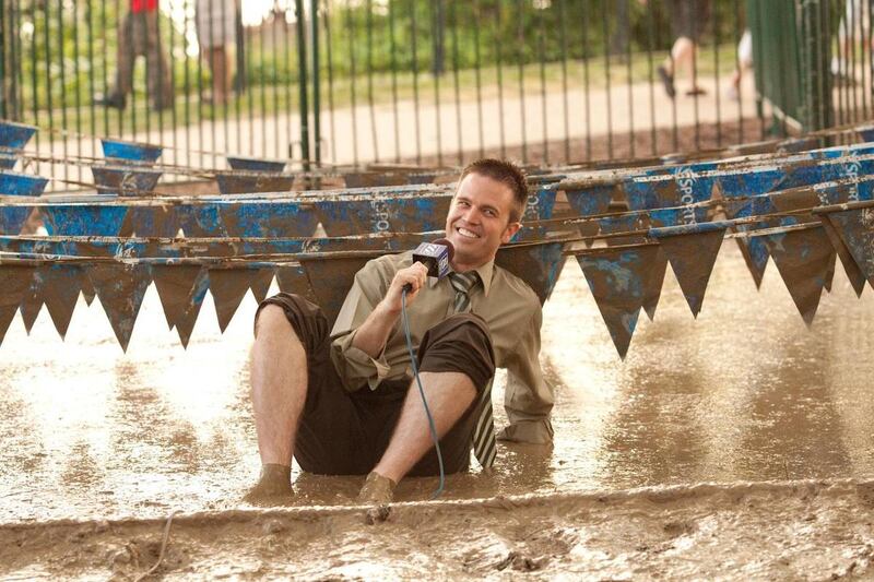 Nate Eaton sits in a vat of mud while covering a muddy fun run.