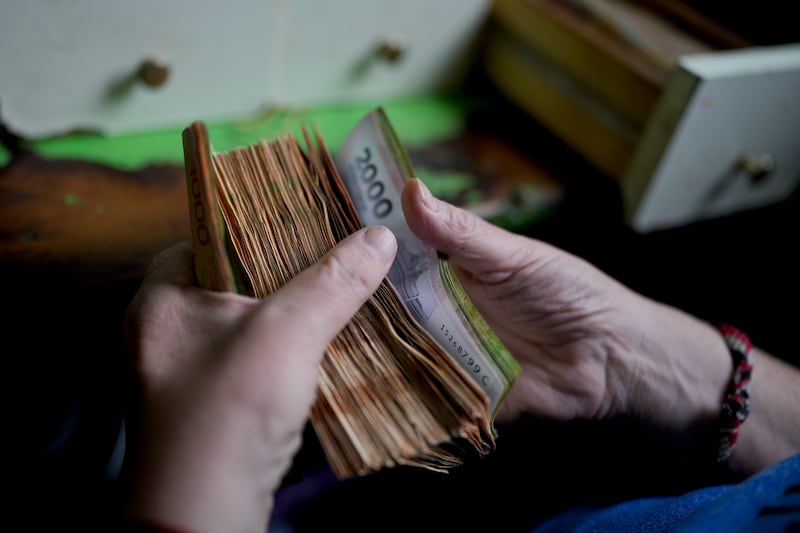 A worker counts money at a grocery store in Buenos Aires on Nov. 21, 2023. In the past five years, Argentina’s currency has lost about 90% of its value against the U.S. dollar.