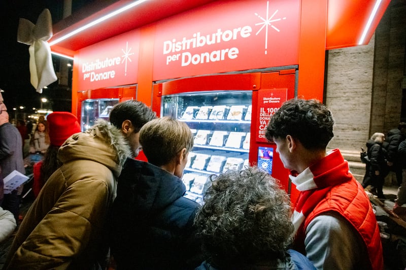 A volunteer assists guests as they choose an item to donate at one of the new Giving Machines in Rome, Italy, on Monday, Dec. 8, 2025.