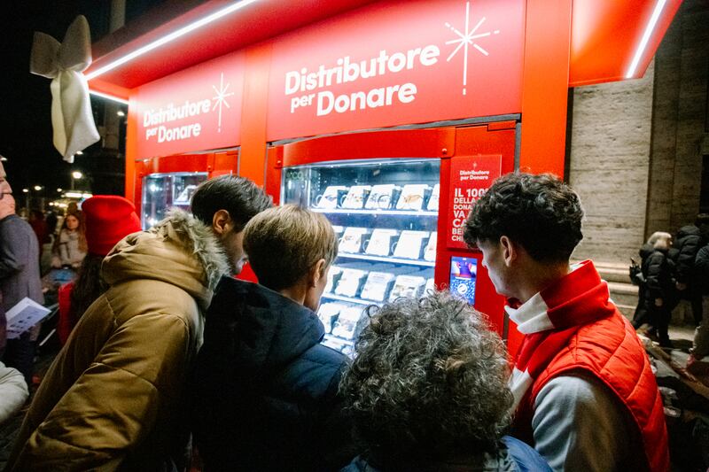 A volunteer assists guests as they choose an item to donate at one of the new Giving Machines in Rome, Italy, on Monday, Dec. 8, 2025.