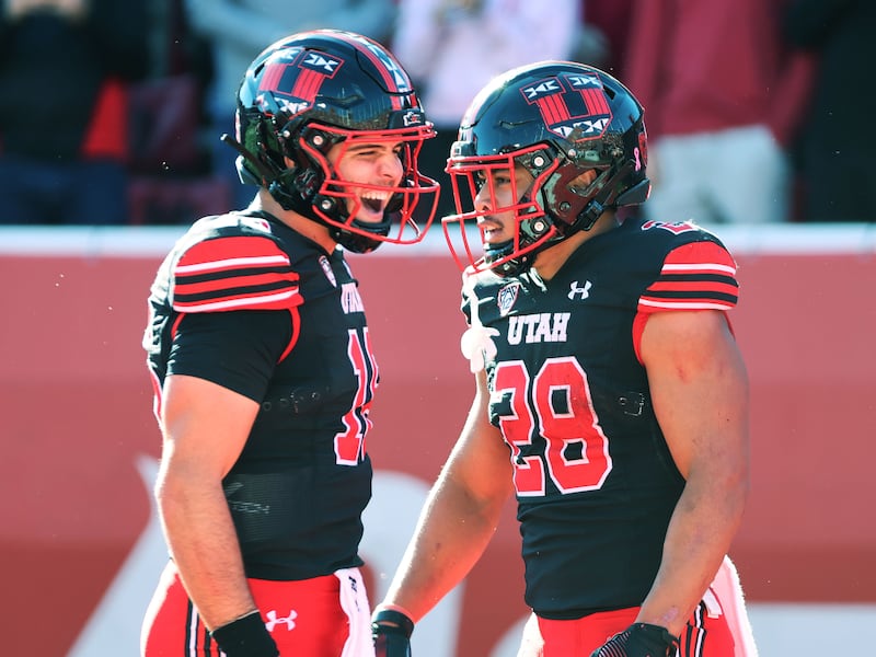 Utah Utes safety Sione Vaki (wearing black) celebrates his touchdown with Utah Utes quarterback Bryson Barnes (wearing black)