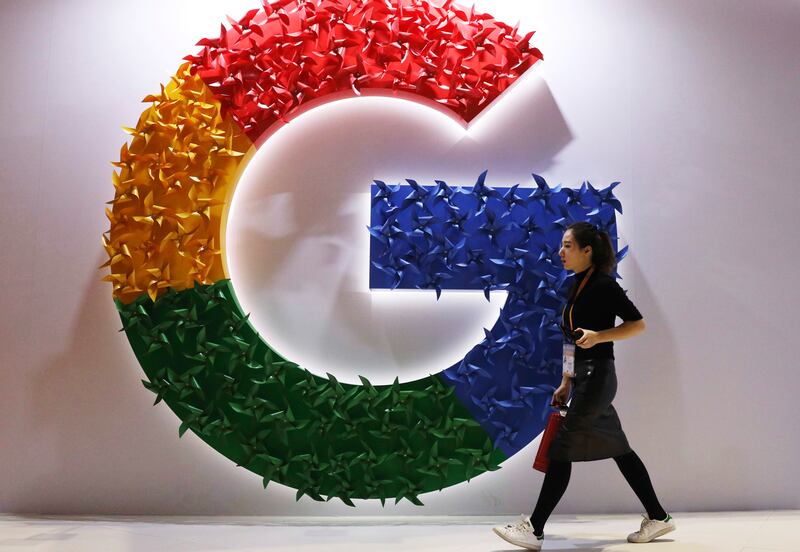 A woman walks past the logo for Google at the China International Import Expo in Shanghai.