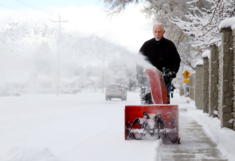 Scott Walker uses his snowblower to remove snow from the sidewalks around his home in Murray as snow falls along the Wasatch Front.