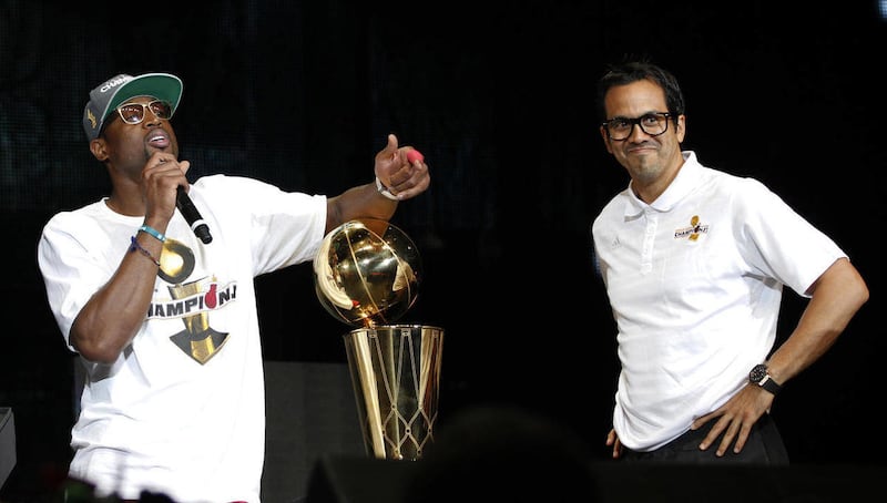 Miami Heat's Dwyane Wade talks to the fans as head coach Erik Spoelstra smiles during a public celebration of the NBA Champions at the arena in Miami, Monday, June 25, 2012.