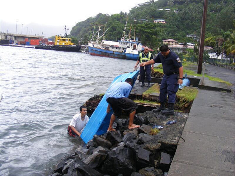 Teenagers remove their aluminum boat from Pago Pago Harbor, as police officers observe as Tropical Cyclone Rene approaches American Samoa on Friday.