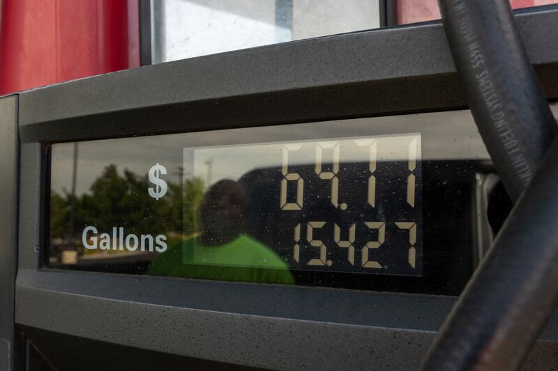 Jesse Griffin can be seen in the reflection in the Maverik gas station pump screen as he fills his truck with fuel in Midvale.