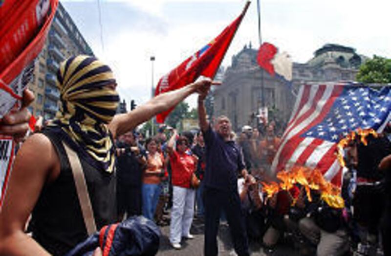 Demonstrators set fire to a U.S. flag Friday in Santiago, Chile, as they protest this weekend's APEC summit and Bush's visit.