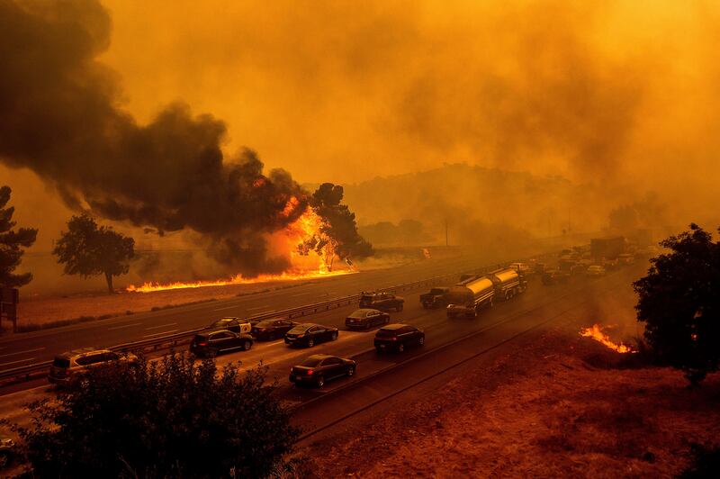 In this Wednesday, Aug. 19, 2020, file photo, flames from the LNU Lightning Complex fires jump Interstate 80 in Vacaville, Calif.