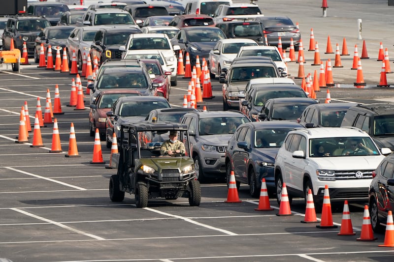 In this Nov. 23, 2020, file photo, vehicles wait in line at a COVID-19 testing site at Hard Rock Stadium in Miami. After a punishing fall that left hospital struggling, some Midwestern states are seeing a decline in new coronavirus cases. But the signs of improvement are offset by the infection’s accelerating spread on both coasts.