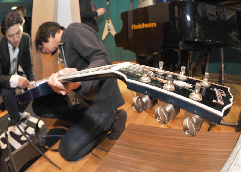 Reporters try out the "robot guitar" in Tokyo. The Les Paul model tunes itself in about two seconds.