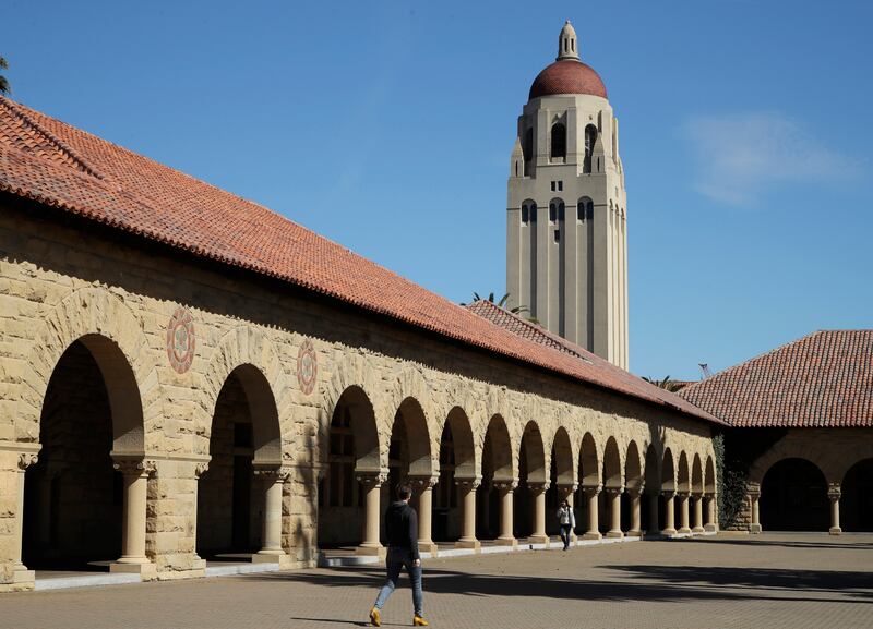 People walk on the Stanford University campus beneath Hoover Tower in Stanford, Calif., on March 14, 2019.