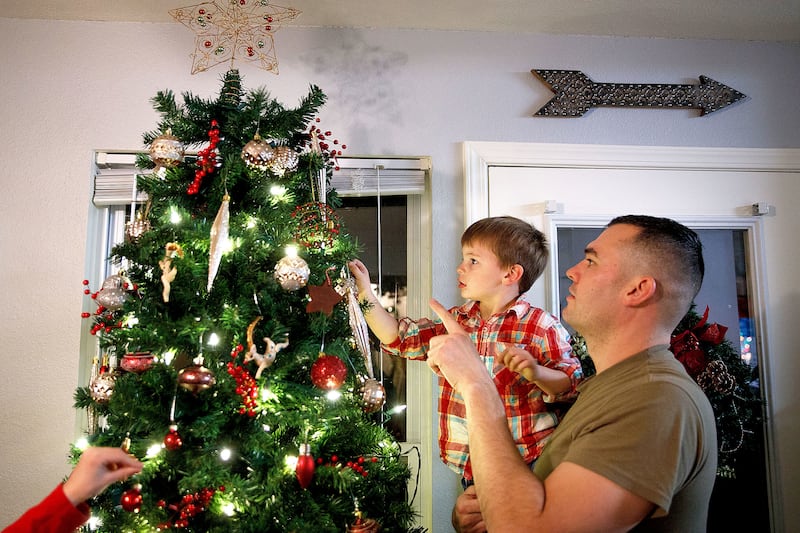 Doug Aliano, right, helps his son, Vincent, 4, place an ornament on the Christmas tree on Wednesday, Nov. 28, 2018, at their home in Bellevue, Nebraska. Doug's wife, Heather Aliano, limits the number of gifts her four children receive at Christmas.