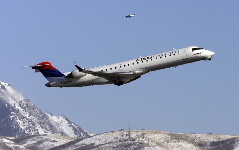 A Delta airplane takes off as a small airplane circles at the Salt Lake International Airport in Salt Lake City Tuesday, Jan. 17, 2012.