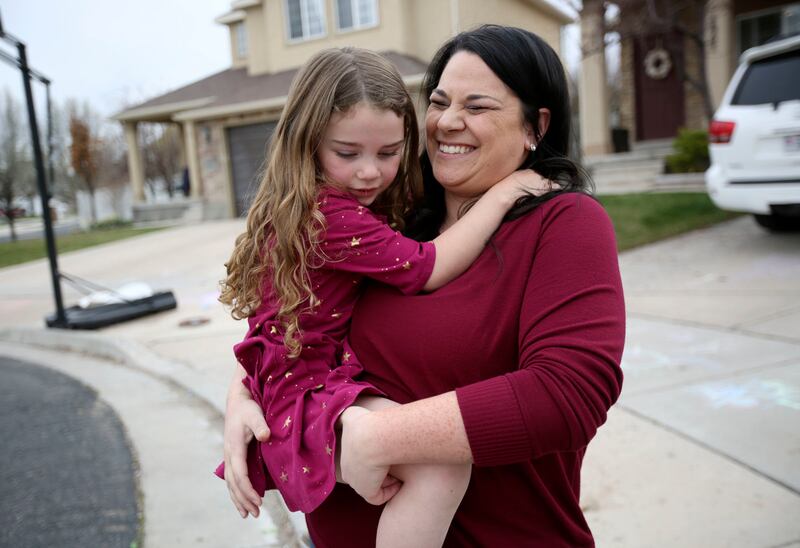Sarah Smith consoles her daughter Delilah, who is afraid of a bug below her, outside of their home in Riverton, Utah, on Monday, April 8, 2019. The Smiths follow Dave Ramsey's cash-only envelope system.