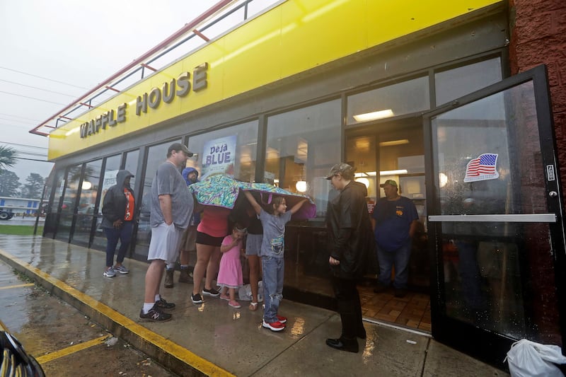 Luke Churchill, left, stands with his wife, Mary and their children, Katie, 13, Liam, 9, and Raighan, 3, as they wait in the rain outside an open Waffle House restaurant in Wilmington, N.C., after Hurricane Florence traveled through the area Sunday, Sept.