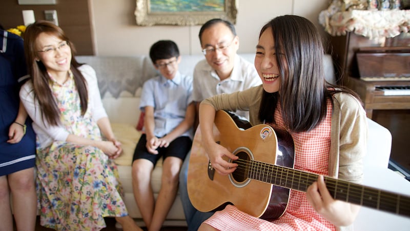 A family sings together with a guitar in their home. Families can practice the new hymns from “Hymns — For Home and Church."