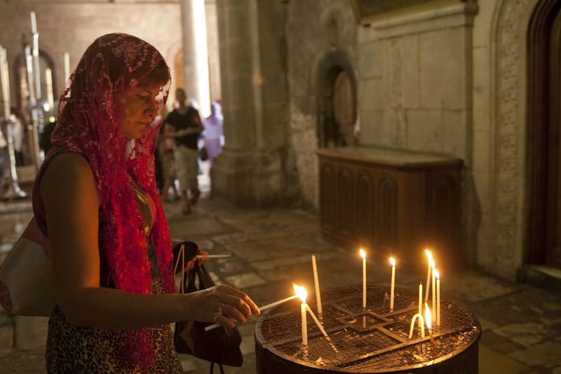Woman lights candle in the Church of the Holy Sepulchre in the Old City of Jerusalem. This site is holy to Catholics and other Christians, who believe it stands on the ground where Jesus of Nazareth was crucified by Roman soldiers. It also marks the site