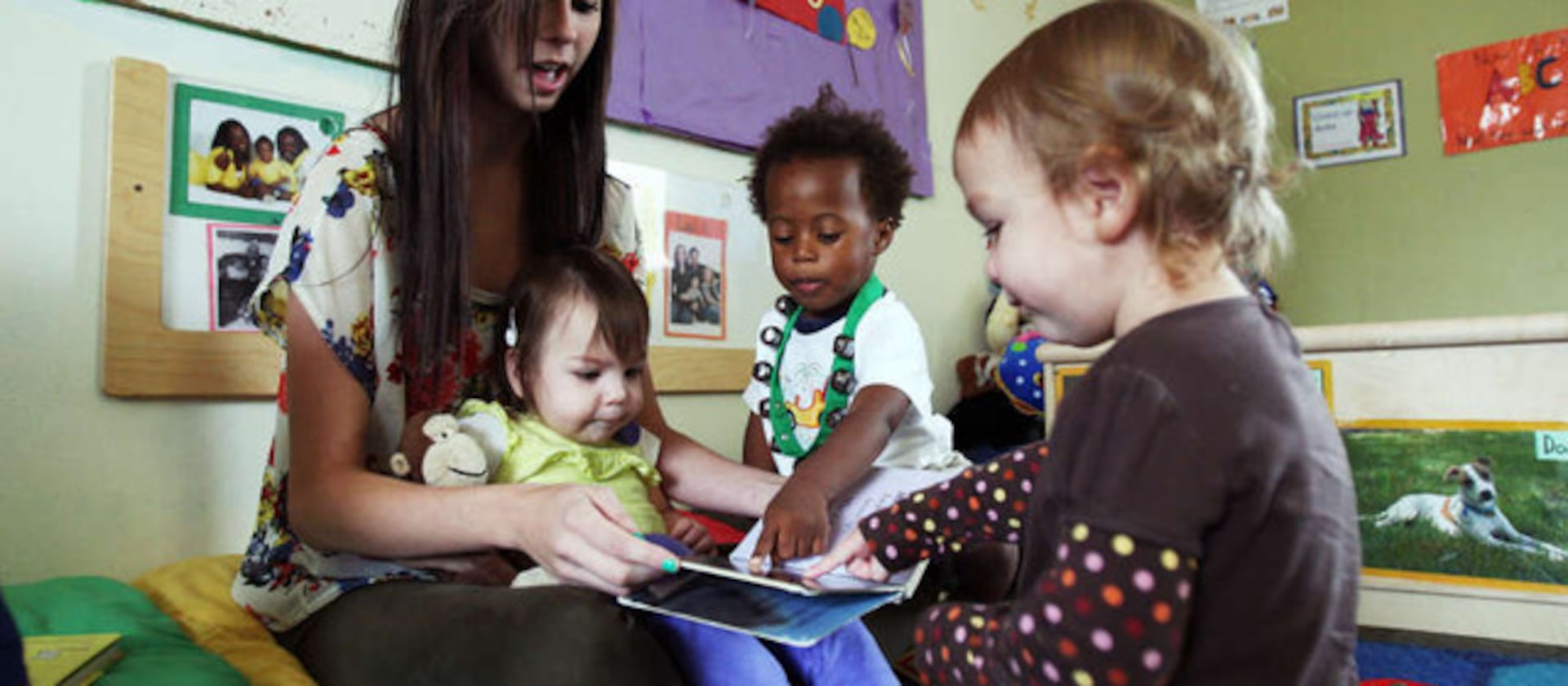 Brittany Palmer holds Isabella Uriarte and she reads to Je’Vanko Stewart and Lillian Jacoby, right, at Utah Valley University.