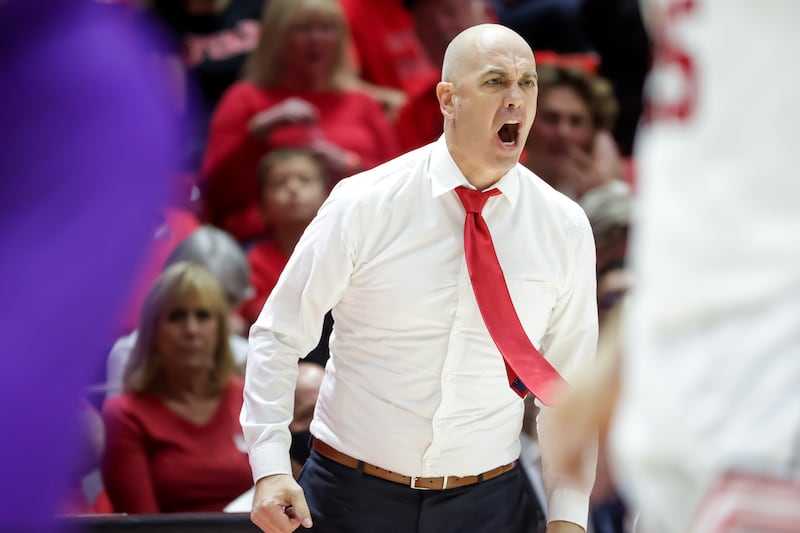 Utah Utes head coach Craig Smith, wearing a suit and tie, reacts to a foul call against his team