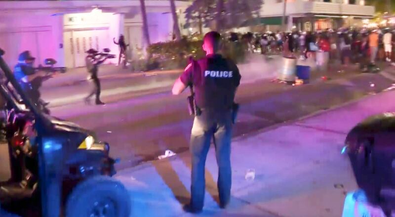 In this image taken from video, SWAT officers in bulletproof vests disperse pepper spray balls on Saturday evening, March 20, 2021, to break up rowdy, spring break crowds that descended on Miami’s South Beach by the thousands, trashing restaurants and flooding the streets without masks or social distancing despite COVID-19 restrictions.