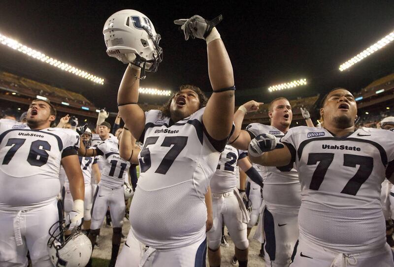 Utah State guard Funaki Asisi (76), Havea Lasike (57) and Al Lapuaho (77) along with the rest of the Utah State football team celebrate their 35-31 win of Hawaii with their fans at the end of a NCAA college football game Saturday, Nov. 5, 2011, in Honolul