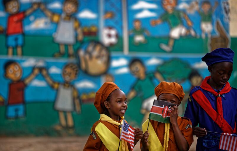 Kenyan girl guides holding U.S. and Kenyan flags await the arrival of the U.S. ambassador at a site supported by PEPFAR in 2018.