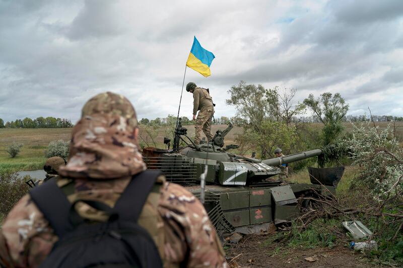 A Ukrainian national guard serviceman stands atop a destroyed Russian tank.