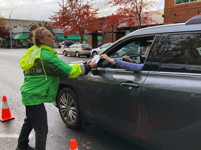 John Kennedy, who was hired by Marion County, Oregon, through a staffing service, accepts a ballot from a voter in downtown Salem, Ore., across from the county clerk’s office.