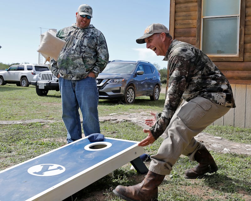 Rich Herbert (left) and his brother-in-law Ty Detmer joke during a game of cornhole on Detmer's T14 Ranch Thursday, Nov. 15, 2018, near Freer, Texas.