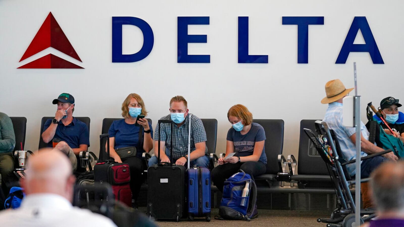 People sit under the Delta sign at Salt Lake City International Airport.