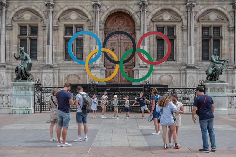 People gather at the Olympic rings at the City Hall in Paris.