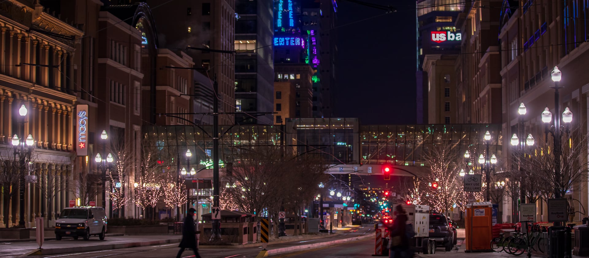People walk through downtown Salt Lake City, with the Walker Center tower lit up in the background