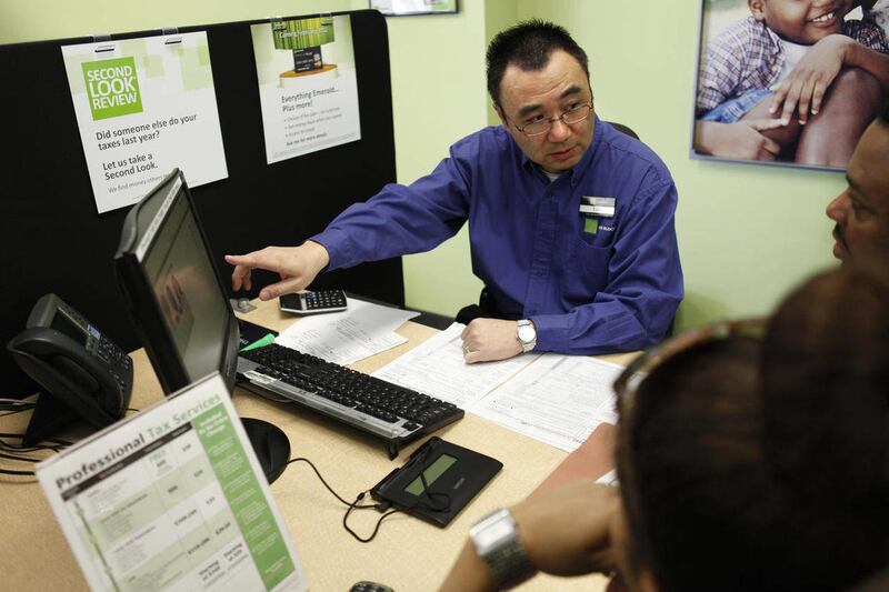 In this Friday, Jan. 6, 2012 photo, Tai Sung, a master tax advisor for H&R Block, center, consults with clients about their taxes at his office in Rockville, Md.