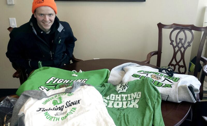In this Feb. 9, 2016 photo provided by Marlys Lord Carlson, University of North Dakota freshman Nick Carlson smiles over his haul of UND Fighting Sioux gear that he bought at Ralph Engelstad Arena in Grand Forks, N.D. The merchandise is part of the Dacota