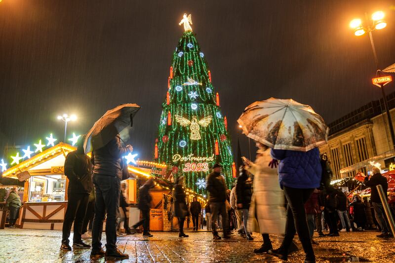 People watch the traditional 45 meter high Christmas tree in heavy rain at the Christmas market in Dortmund, Germany, Monday, Nov. 27, 2023.