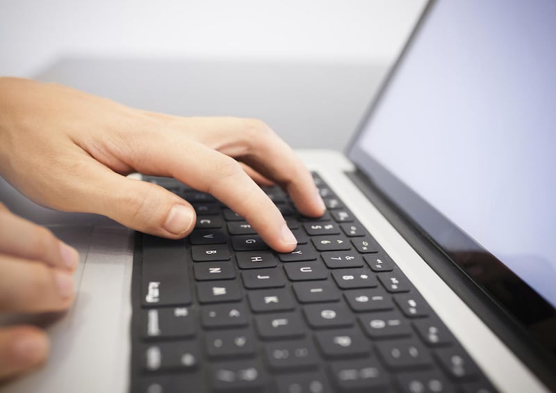 A person types their password on their laptop.