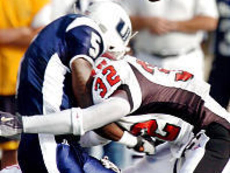 USU's Raymond Hicks gets crunched by a pair of Ute defenders.
