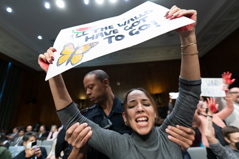 A protester is escorted out of the hearing room by a Capitol Police officer on Capitol Hill in Washington on Oct. 31, 2023.
