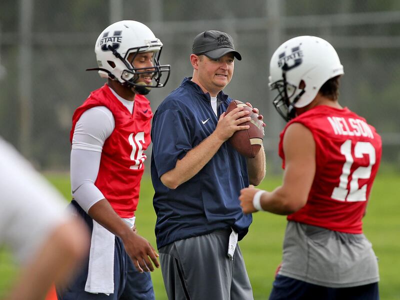 New offensive coordinator Josh Heupel is framed between quarterbacks Chuckie Keeton, left, and DJ Nelson during Utah State football practice Aug. 7, 2015, in Logan.