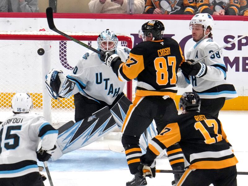 Pittsburgh Penguins' Sidney Crosby (87) attempts to swat the puck out of the air in front of Utah Hockey Club goaltender Karel Vejmelka (70) with Liam O'Brien (38) defending during game Saturday, Nov. 23, 2024, in Pittsburgh. The two teams meet again Wednesday night in Salt Lake City.