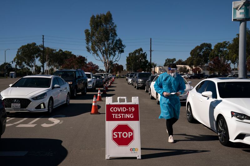 In this Nov. 16, 2020, file photo, student nurse Ryan Eachus collects forms as cars line up for COVID-19 testing at a testing site set up the OC Fairgrounds in Costa Mesa, Calif.