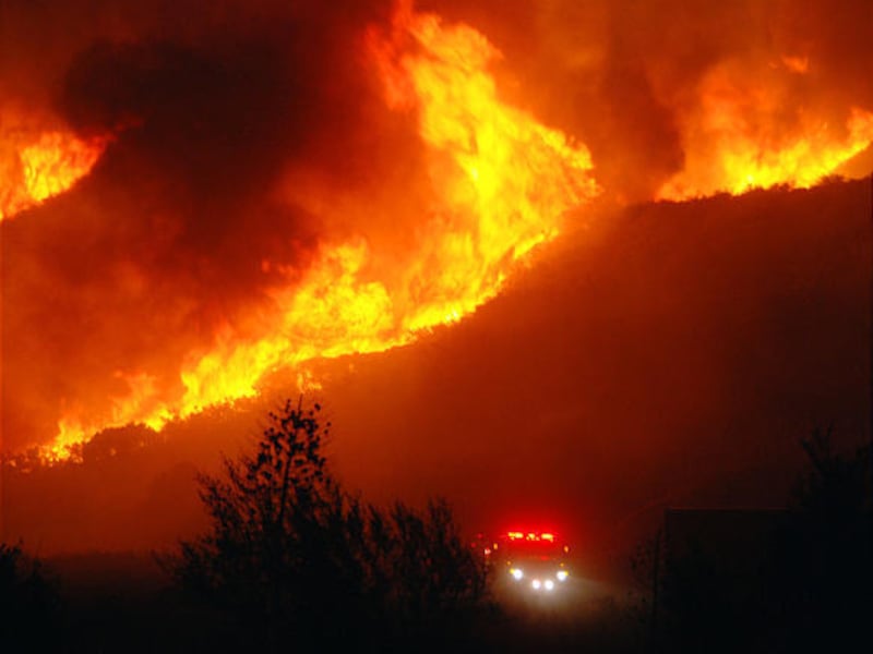 Fire races over a ridge as a fire truck makes its way along Lone Pine Canyon road in the San Gabriel mountains.