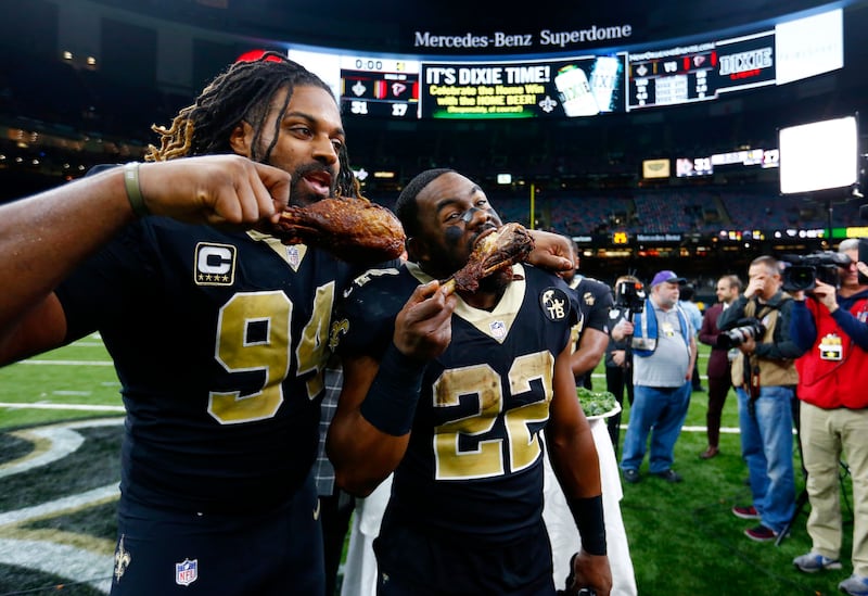 New Orleans Saints defensive end Cameron Jordan (94) and running back Mark Ingram (22) eat turkey drumsticks after their Thanksgiving night game in 2018.
