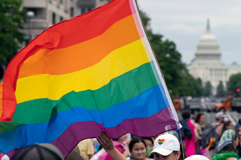 A person waves a rainbow flag as they participate in a LGBTQIA+ rally near the U.S. Capitol.