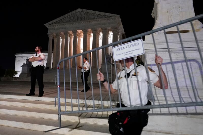 Police move barricades in place as a crowd of people gather outside the Supreme Court, Monday in Washington.